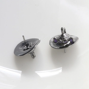 Close-up of black witch hat earrings with purple ears and bow accents on white surface