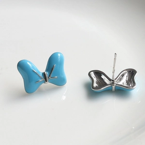 Detailed view of light blue bow stud earrings with polished silver needles