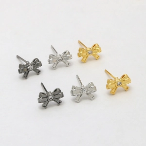 Detailed view of bow-shaped stud earrings in gold, silver, and gun black with small crystals