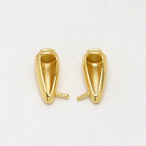 Close-up of polished gold-plated horn-shaped jewelry findings with spiral ends