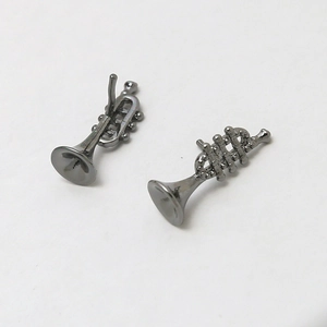 Macro detail of gunmetal trumpet earrings with precise musical instrument craftsmanship