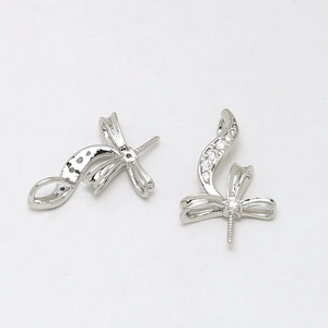 Detail of silver bow jewelry finding with white zircon inlay and pearl pin connector