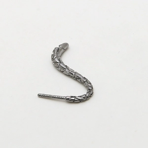 Macro detail of snake-shaped gunmetal stud earring with intricate textured scales