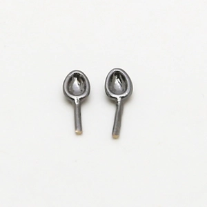 Macro detail of spoon-shaped earring accessories in matte black metal finish