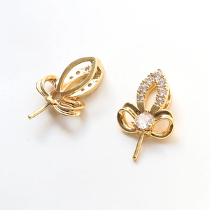 Close-up of gold-plated leaf and bow pendant charms with zircon pavé for pearl jewelry