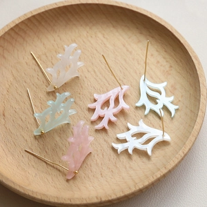 Detail of elegant filigree acetate antler charms in pastel colors on a wooden tray