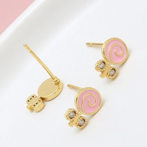 Détail macro des boucles d'oreilles sucette émail rose avec placage or et zircones