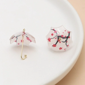 Close-up of DIY umbrella charms with cherry blossom prints and gold-tone metal handles