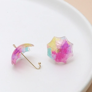Close-up of mini resin umbrella charms with colorful watercolor swirls and gold hooks
