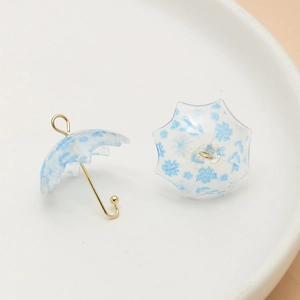 Detailed view of mini floral umbrella charms with golden handles for DIY jewelry making