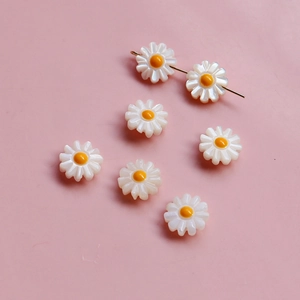 Vue macro de 7 perles de marguerite en coquille blanc et jaune pour bijoux DIY
