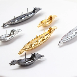 Detailopname van gouden en zilveren drakenbootbedels voor DIY-parelsieraden ontwerpen