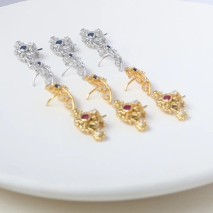 Close-up of vintage hollow floral crown pendants with red and blue zircon inlay