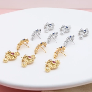 Detailed view of vintage gold crown earring studs with red and blue zircon stones