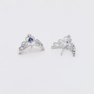 Detailed view of silver crown earrings with blue cubic zirconia and filigree patterns