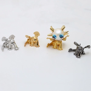 Vue détaillée de supports de bijoux en forme de dragon en or, argent et noir avec perles
