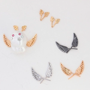 Detail of wing-shaped DIY jewelry charms with gold-plated wings on baroque pearl