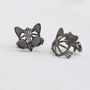 Detalle de cabezas de zorro en metal negro con circonitas brillantes y gafas redondas