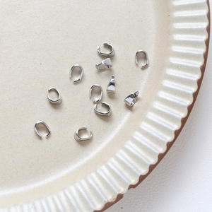 Gros plan d'attaches de pendentif en métal argenté pour bijoux sur une assiette crème