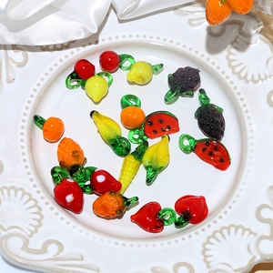 Detailed view of handmade colorful glass fruit beads for DIY jewelry in a white plate