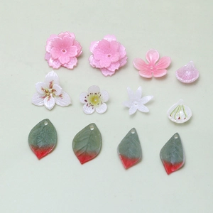 DIY jewelry parts featuring pink cherry blossoms, white lilies, and green leaves