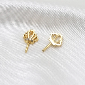 Gros plan sur des boucles d'oreilles couronnes dorées avec des pierres en zircone