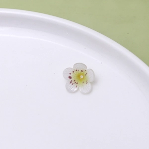 Detailed close-up of handmade white flower bead with yellow center for DIY floral jewelry