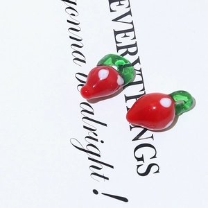 Macro view of two handmade red strawberry glass beads for DIY jewelry making