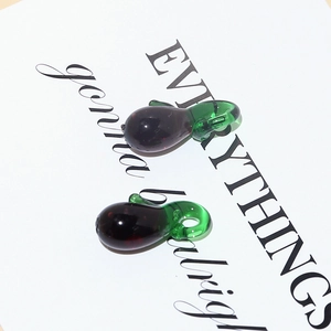 Detailed view of two glossy glass eggplant charms for DIY jewelry making and crafts