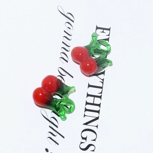 Detail shot of glass cherry charms for DIY jewelry making with green leaf and red berry