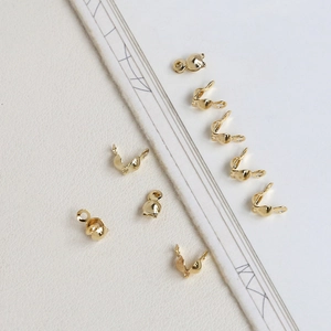 Detail view of 14k gold-plated bead tips for DIY jewelry making on white paper