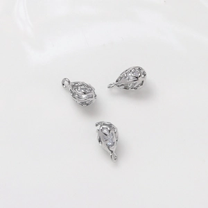 Macro detail of three silver drop earrings with petal hollow design and white zircon inlays