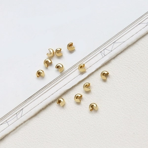 Macro detail of 14k gold-plated C-shaped crimp beads for jewelry making necklaces