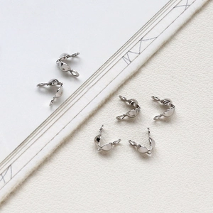 Detailed view of silver-plated U-shaped fold-over crimp bead covers for jewelry making