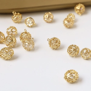 Detail view of gold-plated woven sphere charm with embedded crystal for DIY jewelry making