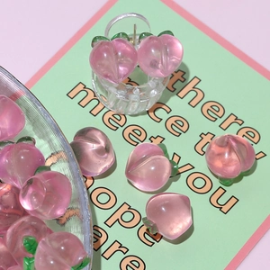 Pink resin peach charms for DIY jewelry and hair accessories on a glass bowl and card