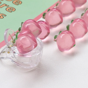 Detailed macro of pink resin peach charms on a transparent hair clip for DIY accessories