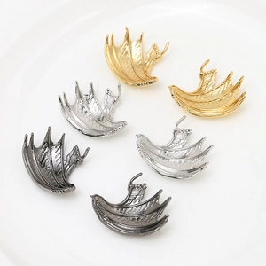 Detailed view of metal wing charms in gold, silver, and black for DIY jewelry making