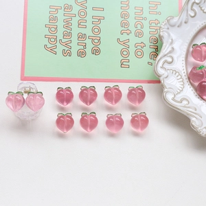 Macro detail of pink resin peach charms and mini hair clips for DIY jewelry making