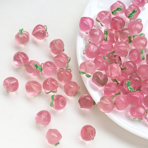 Macro detail of mini pink resin peach charms with green leaves for DIY jewelry making