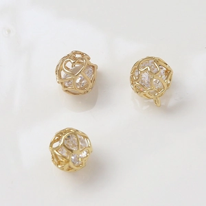 Detailed macro view of 14k gold plated heart cage charms with central round zircon stones