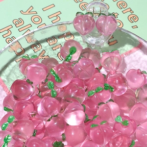 Detailed macro view of pink resin peach charms with green leaves for DIY hair accessories