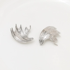 Macro detail of silver-plated dragon wing charms with skeletal texture and metallic finish