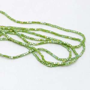 Detailed macro view of 3mm square green crystal beads with AB rainbow coating for DIY jewelry