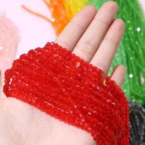 Close-up of 4mm red faceted crystal wheel beads held by hand for DIY jewelry making