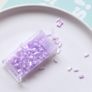 Macro view of 2mm purple bugle beads in a storage box for DIY embroidery crafts
