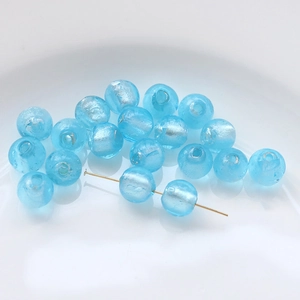Macro shot of light blue translucent glass beads with gold pins for DIY jewelry making