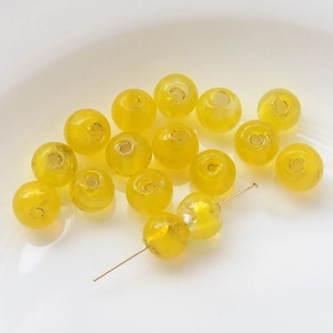 Close-up of yellow glass beads with gold foil inside for DIY jewelry making