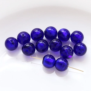 Macro shot of dark blue glass beads with gold specks and holes for DIY jewelry