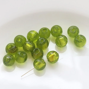 Macro view of translucent grass green glass beads with gold foil for jewelry making